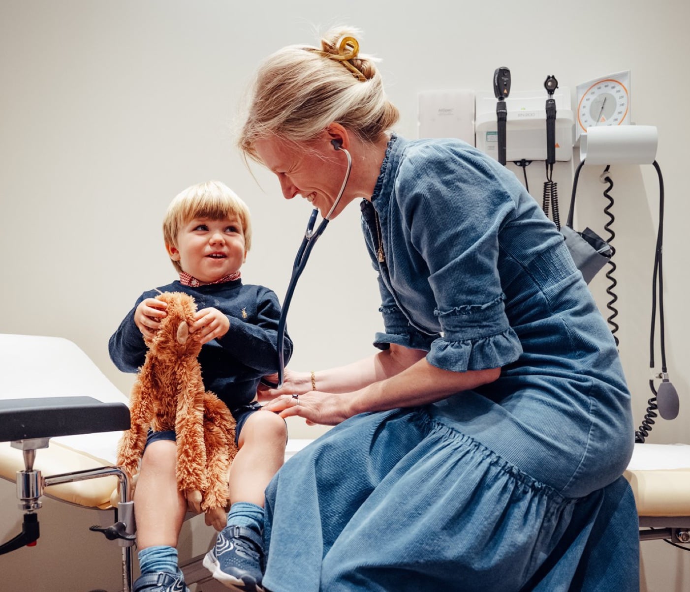 A female GP doctor examining a young boy.