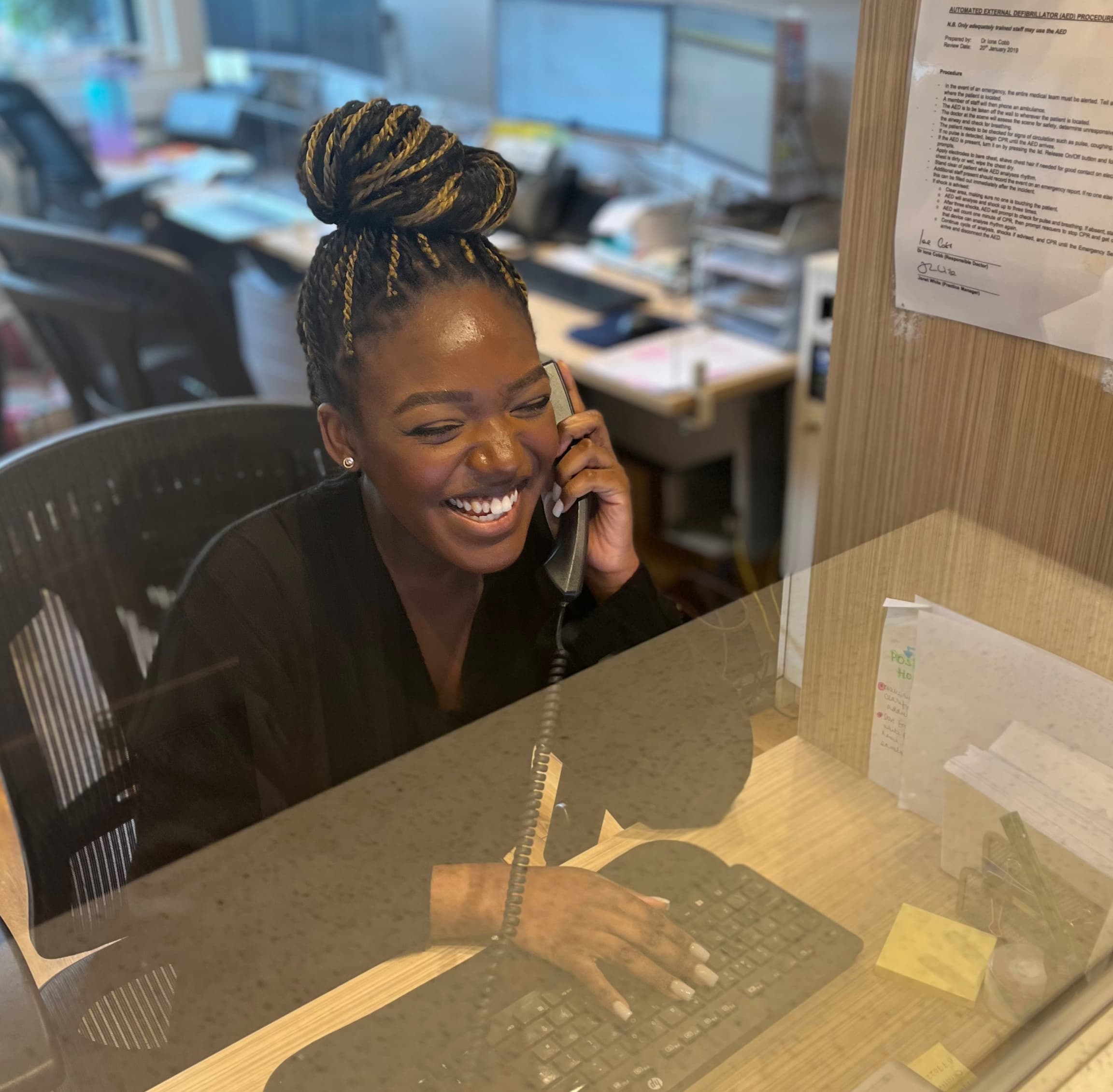 Photo of Anita Asare, receptionist, on the phone in Sloane Street private GP in London.